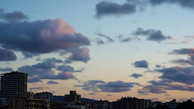 City Skyline at Twilight. Silhouetted buildings and scattered clouds during sunset. Possible for urban planning or travel brochure backgrounds