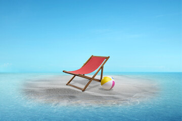 Beach chair and colorful beach ball on a beautiful sandy beach on the island with an ocean view and a blue sky. Summer concept