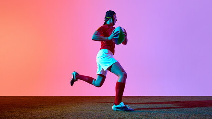 Rugby athlete holding ball in motion against vibrant gradient background. Concept of focus during run, speed and control balance
