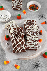 Halloween dessert. Chocolate brownie decorated with chocolate icing in the shape of a mummy and...