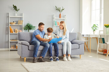 Family spending leisure time together at home with child, assisting with homework or painting in a...