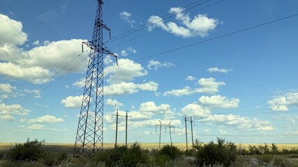 Many high-voltage transmission tower and electricity pylon power lines against blue sky with cloud