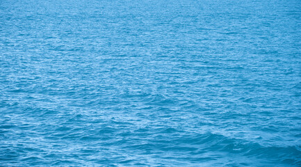 Blue water with ripples on the surface. Defocus blurred transparent blue colored clear calm water surface texture with splashes and bubbles. Water waves with shining pattern texture background.