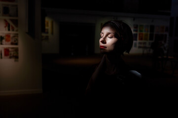 Woman in Focus Under Spotlight in Artistic Exhibition Environment