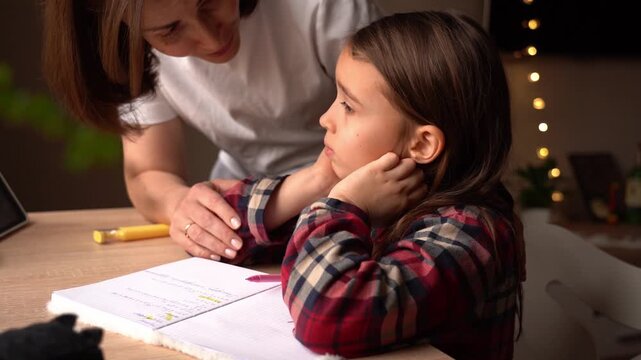 Child struggles with homework while mother offers support in cozy home environment