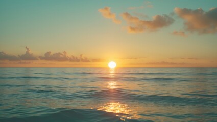 Fototapeta premium Sunset over the ocean with the sun near the horizon, reflecting on calm waters, under a partly cloudy sky.