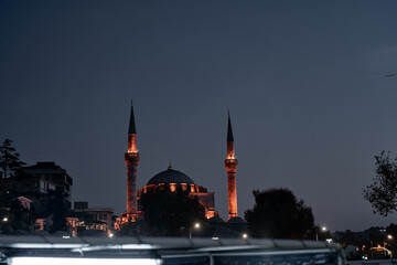 A magnificent mosque with lit minarets stands against a twilight evening sky, emphasizing...