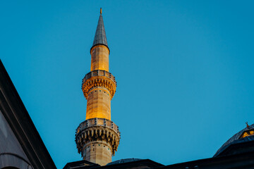 Illuminated Minaret Towering Against a Clear Blue Sky in Evening Light