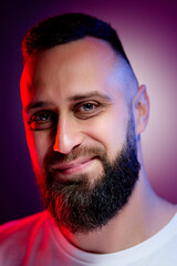 Studio portrait with colorful light of young handsome bearded man.