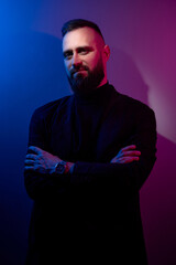 Studio portrait with colorful light of young handsome bearded man.