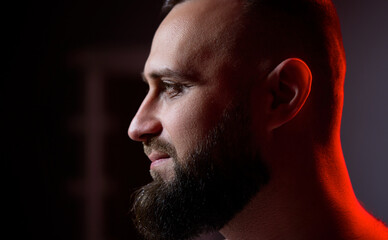 Studio portrait with colorful light of young handsome bearded man.