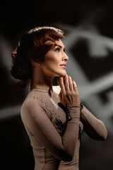 Portrait of beautiful young lady with wave hairstyle wearing elegant dress. Retro-inspired girl in...