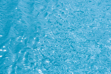 Blue water with ripples on the surface. Defocus blurred transparent blue colored clear calm water surface texture with splashes and bubbles. Water waves with shining pattern texture background.