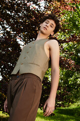 Young man in stylish summer outfit enjoys sunlight in vibrant green park