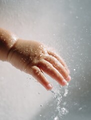 Fototapeta premium Focus on the back of an Asian child's hand as water drops slowly flow on the skin, looking moist and touchable. Use natural light, clean tone background.