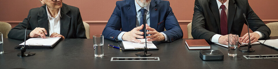 Three middle aged politicians sitting at conference table discussing documents and preparing for...