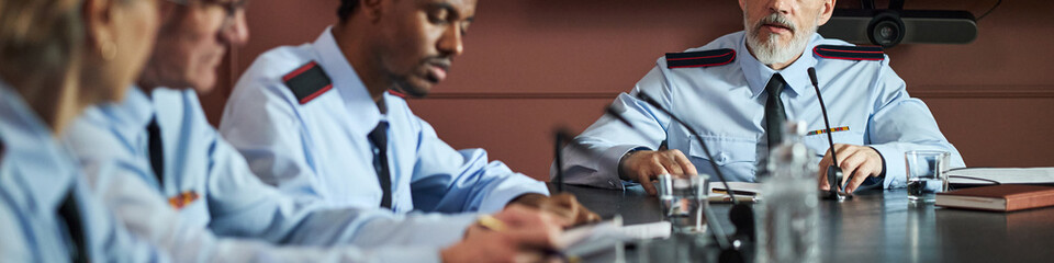 Group of middle aged and senior Caucasian and Black men wearing uniform shirts, sitting at...