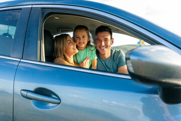 The family is sitting in the car, they are ready for a family trip before going to school at the...