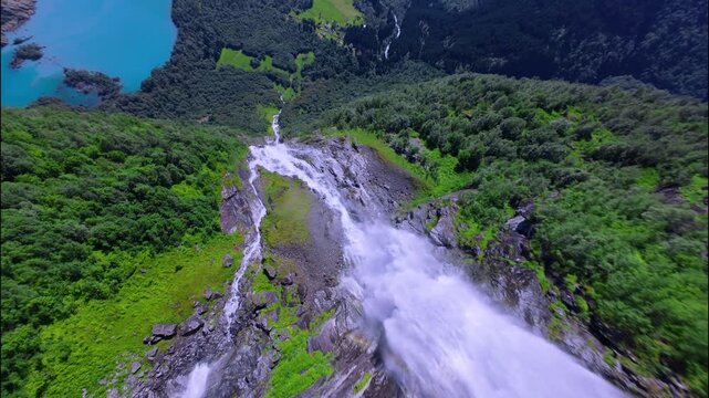 Cinematic FPV drone flight over a stunning waterfall cascading from the turquoise waters of Lake Lovatnet, surrounded by steep cliffs and lush Norwegian landscape. Shot in 4K and stabilized