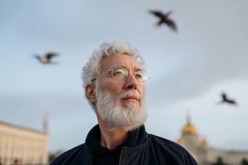 Elderly caucasian male in urban setting with birds in background