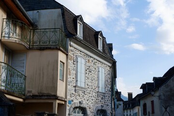 Two stone buildings with balconies line a peaceful street. The architecture features charming detail