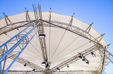 Central structure of a large outdoor canopy displaying metal framework and lights during an event...