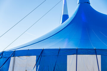 Bright blue circus tent raised in a bustling outdoor location, preparing for exciting performances...