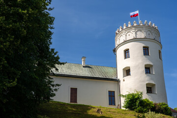 Przemyśl Castle in Poland – historic hilltop fortress with round tower and national flag, showcasing heritage architecture under a clear blue summer sky