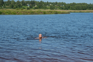 Mature adult woman is swimming in a river on vacation.