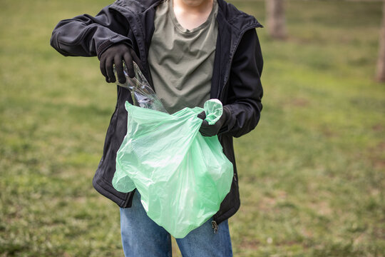 Teenager kid boy picking up trash plastic bottles in the park. Volunteer concept. Ecology, recycling concept. Earth day 22 April. World Environment Day. Save planet.