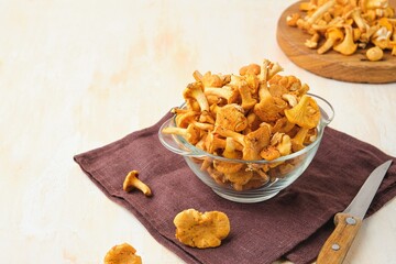 Fresh chanterelles in a glass bowl on a light concrete background. Wild mushrooms, gifts of the...