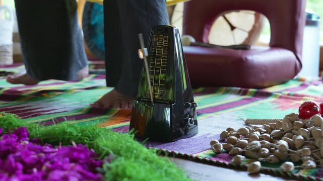 An old mechanical metronome stands on the floor counting down the rhythm