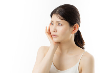 肌の悩みを気にする若い女性の表情（白背景）