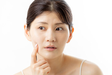 肌の悩みを気にする若い女性の表情（白背景）