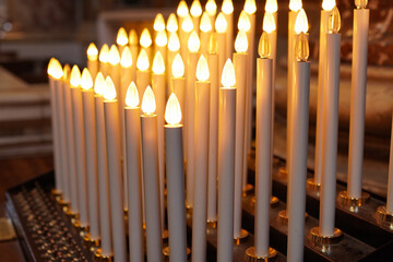 Closeup of Church candles lit with offerings	