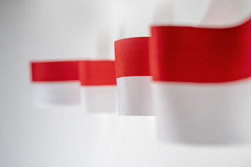 The striped red and white ribbon of the Indonesian flag on a white background. Concept of Indonesian Independence Day or Kemerdekaan
