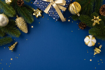 Festive gold and white Christmas decorations with evergreen branches and a gift on blue