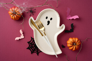 Ghost-shaped dishware amidst Halloween decorations with pumpkins, spiders, and bats creating...