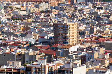 Aerial view of a dense urban landscape showcasing numerous buildings and rooftops of various colors...
