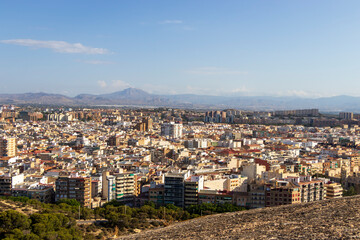 Obraz premium Aerial view of Alicante, Spain, showcasing a vibrant cityscape with modern and traditional architecture under a clear blue sky, ideal for travel and real estate contexts.