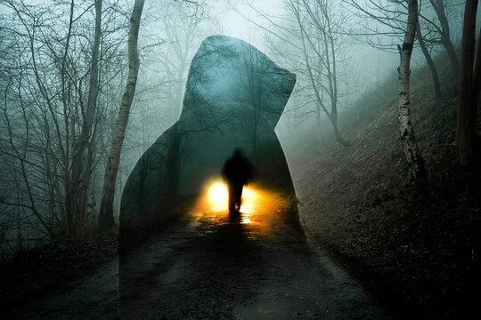 a horror edit of a double expsoure of a ghost like figure. With a blurred ghost figure in front of car headlights. On a spooky foggy winters evening in a forest.
