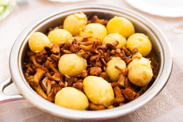 delicious forest mushrooms chanterelles with young potatoes fried in frying pan