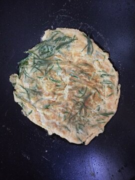 Cha-om omelette frying in pan, traditional Thai food top view