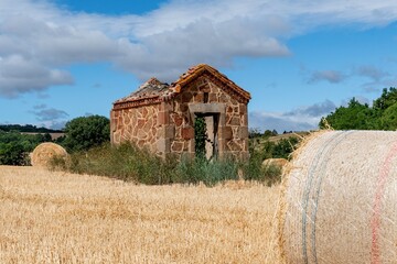 maison de vigne au milieu d'un champ de bleu fraichement coupé avec une botte de paille au premier plan