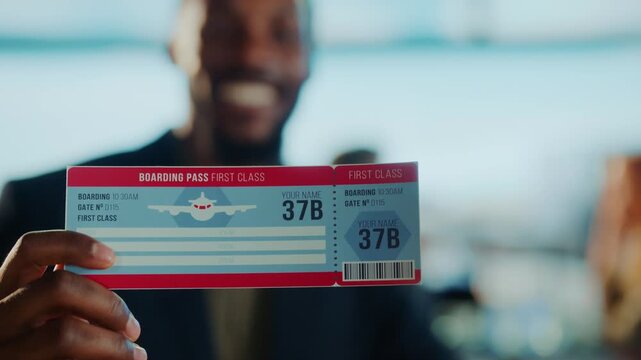 A smiling man holds a boarding pass, first class, ready for his trip.