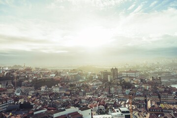 Obraz premium Sunrise bathes Porto in a warm glow. Diverse architecture, including notable cathedrals and traditional buildings, come together in a captivating urban panorama