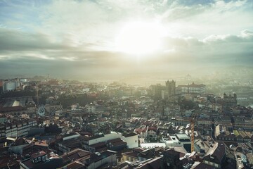 Dramatic morning light bathes Porto. Rooftops stretch towards Vila Nova de Gaia. Prominent...