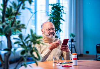 Old Indian man with smartphone and medicine pack verifying ingredients at home