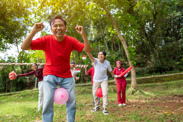Obraz premium Portrait of an Indonesian southeast asian people celebrate Indonesia Independence Day on the 17th of August with a game of keep the balloon from blowing out outdoors. Concept of Kemerdekaan Indonesia