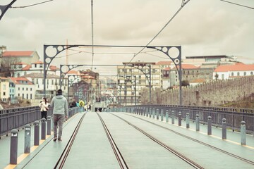 Travelers walk along the Dom Luis I Bridge in Porto. The cityscape with its aged architecture...